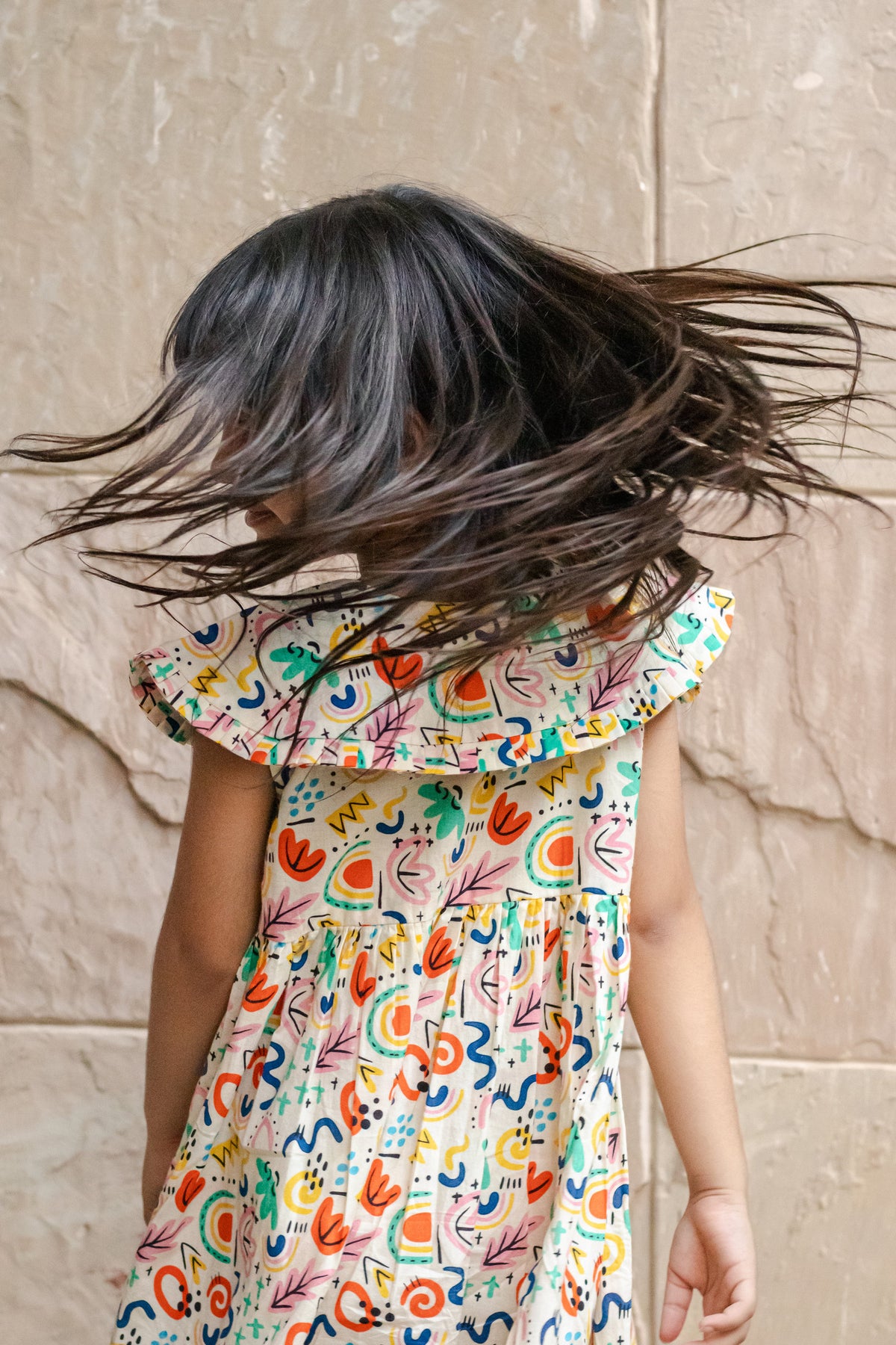 Back view of Basic Tribe Soul Surfer dress showing bright abstract print and flutter sleeves