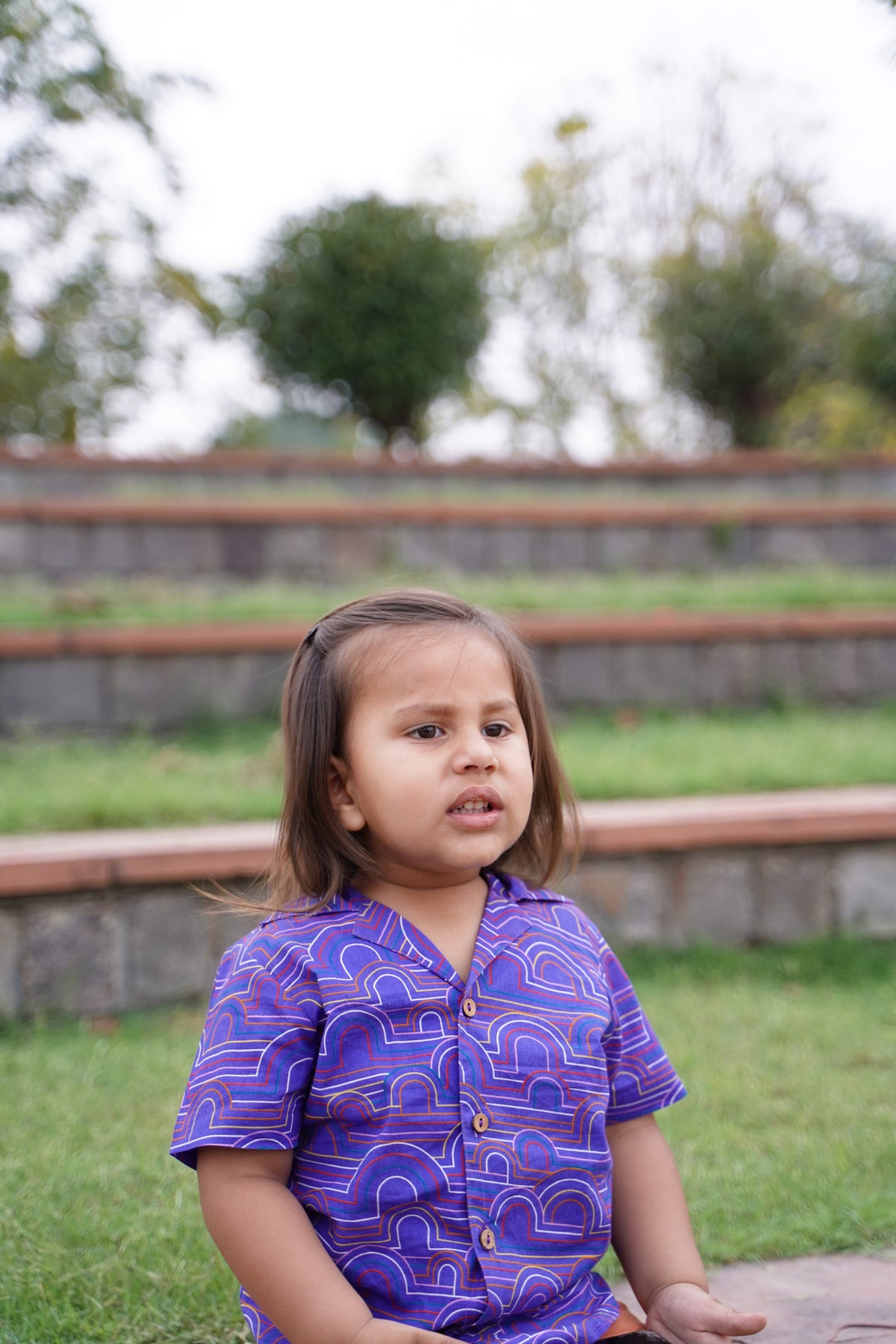 Girl seated in Basic Tribe Aladdin purple short-sleeve printed cotton shirt