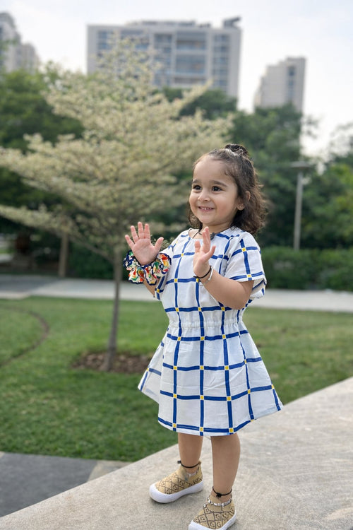 Girl in Basic Tribe Checkmate white cotton dress with blue windowpane checks, front view