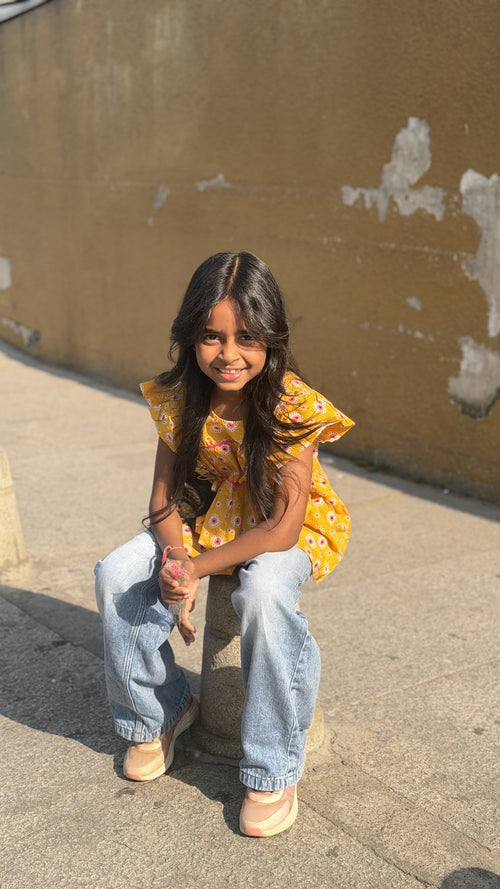 Girl wearing Basic Tribe Pretty Wow yellow floral cotton top with ruffled sleeves