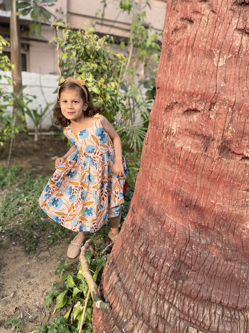 Girl wearing Basic Tribe Muniah sleeveless floral cotton dress with blue and orange print