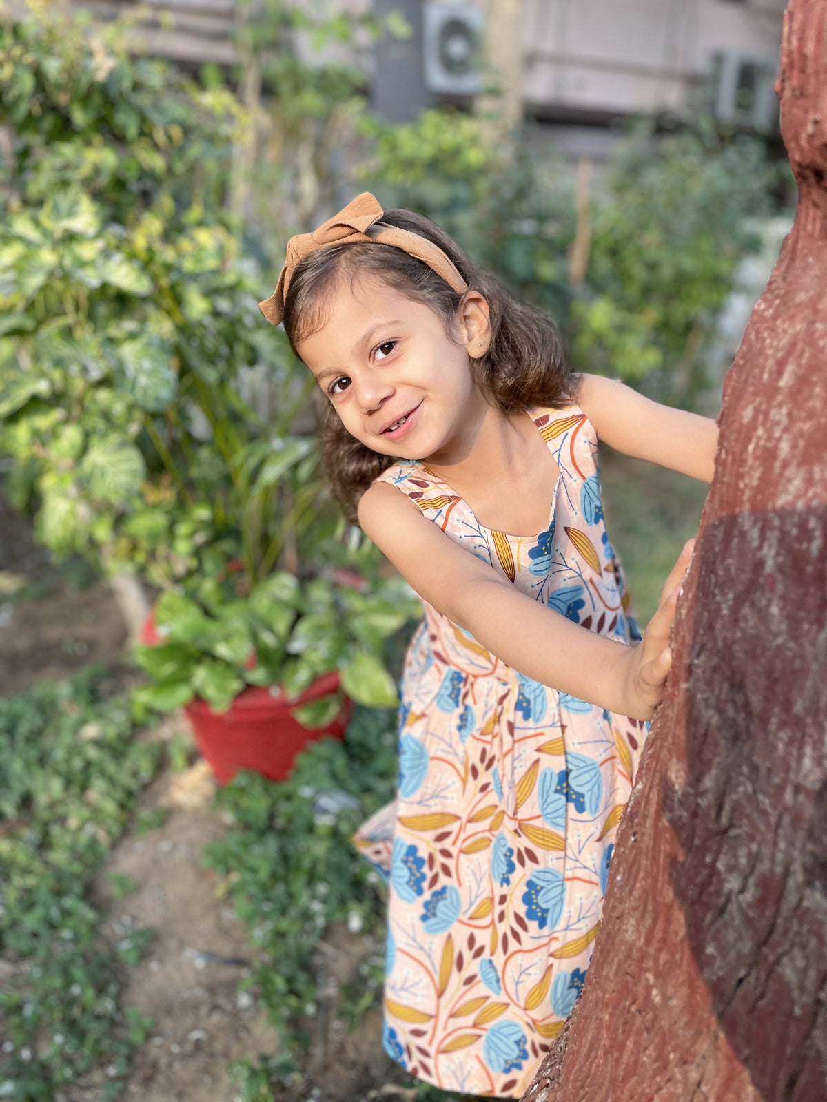 Girl posing beside a tree in Basic Tribe Muniah floral printed cotton dress