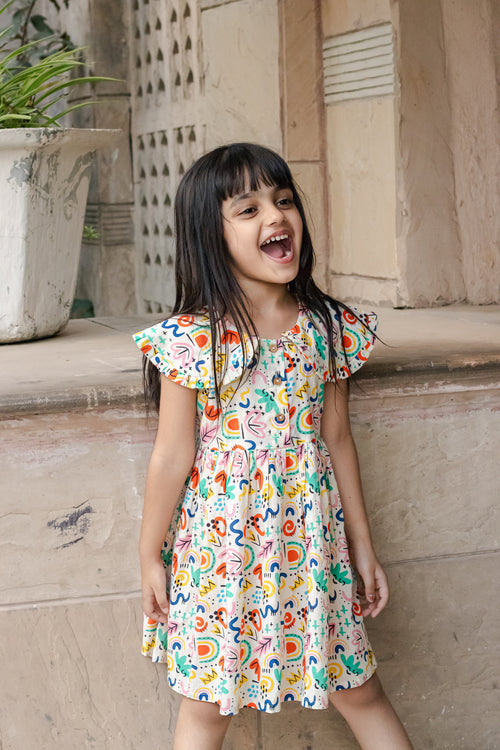 Girl in Basic Tribe Soul Surfer cotton dress with colourful abstract print and ruffle sleeves