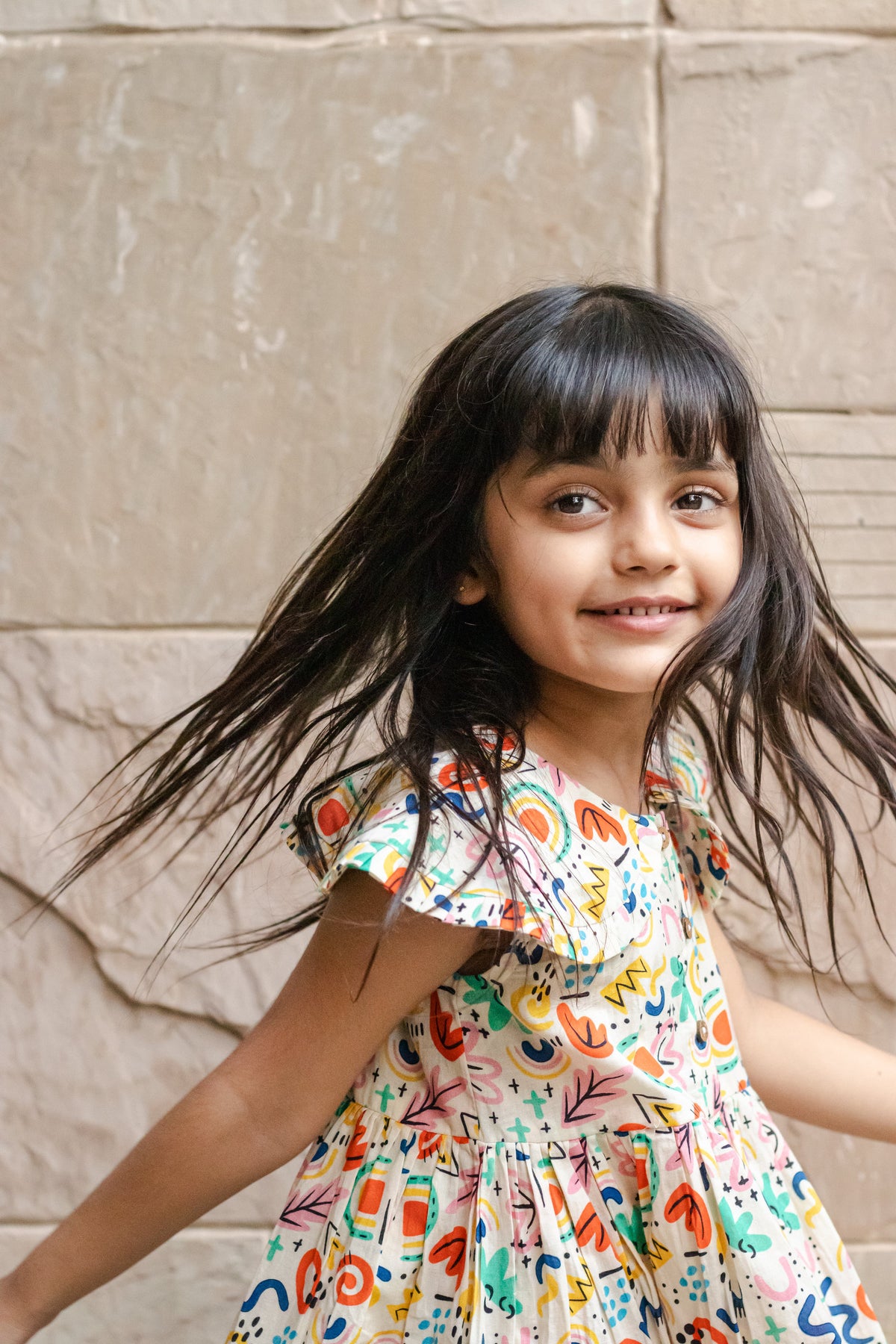 Girl smiling in Basic Tribe Soul Surfer multicolour printed cotton dress, front styling view
