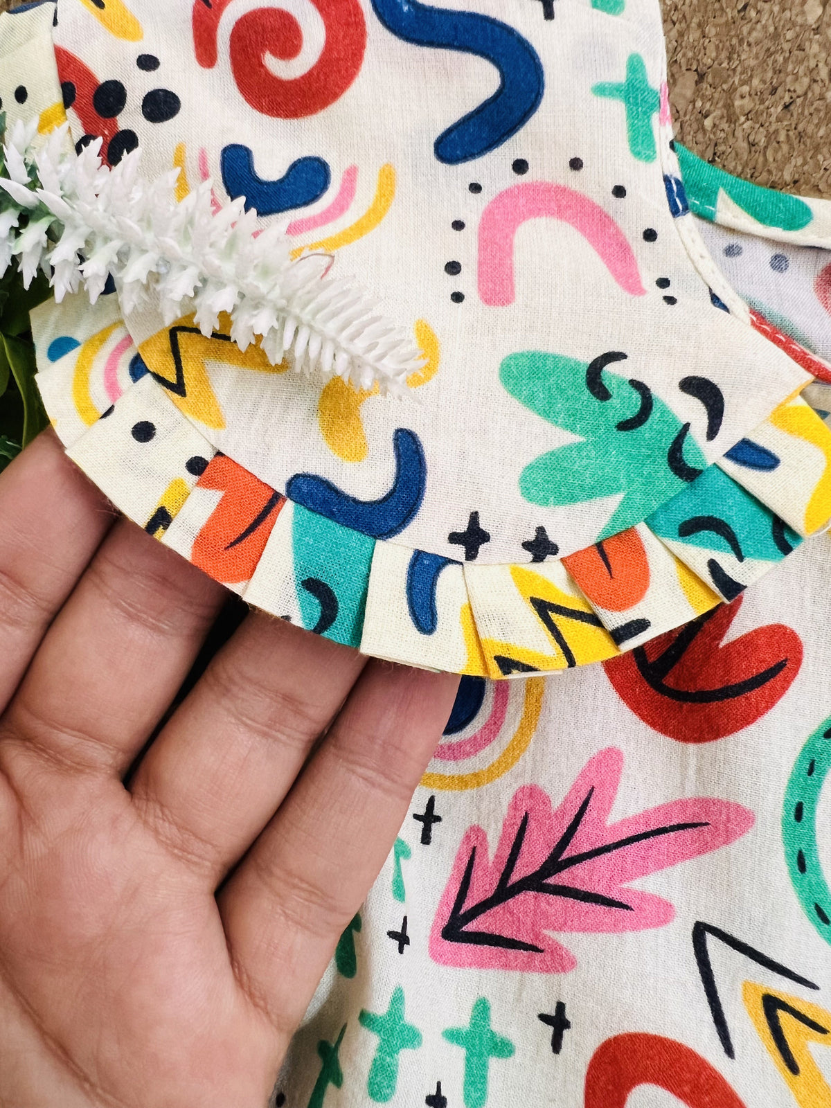 Close-up of Basic Tribe Soul Surfer cotton dress fabric with colourful motifs and trim